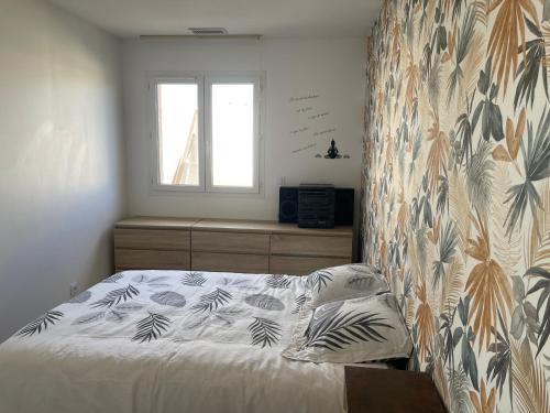 - une chambre avec un lit orné d'un mur fleuri dans l'établissement Villa calme deux chambres proche de la mer tout confort, à Pinet