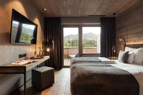 a hotel room with a bed and a large window at Alpenhotel Kitzbühel am Schwarzsee - 4 Sterne Superior in Kitzbühel