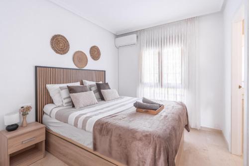 a white bedroom with a large bed and a window at Casa Lisanofa in Orihuela