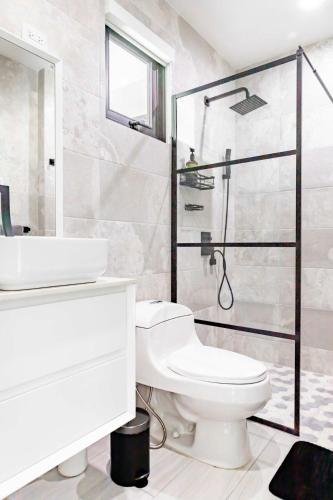 a white bathroom with a toilet and a shower at Renovated 3 BR House in Dorado del Mar in Dorado