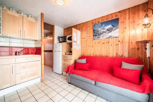 un salon avec un canapé rouge dans une cuisine dans l'établissement Appartement les Oursons, à Morillon