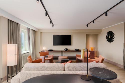 a living room with a couch and chairs and a tv at Radisson Blu Latvija Conference & Spa Hotel, Riga in Rīga