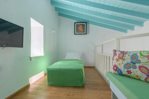 a living room with a green couch and a flat screen tv at Platanos Cottage in Symi