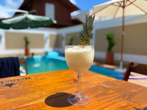 a drink in a glass sitting on top of a table at Casa Vila Say 04 quartos ar e Piscina Aquecida in São Francisco do Sul