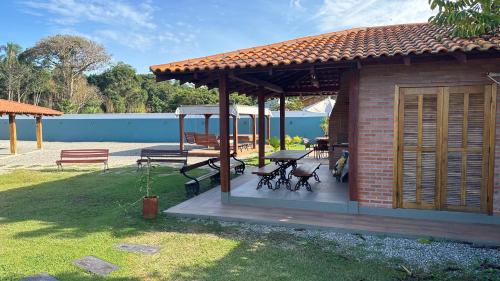 a pavilion with a table and benches in a yard at Casa Vila Say 04 quartos ar e Piscina Aquecida in São Francisco do Sul