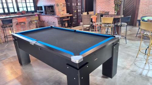 a black pool table in a room with chairs at Casa Vila Say 04 quartos ar e Piscina Aquecida in São Francisco do Sul