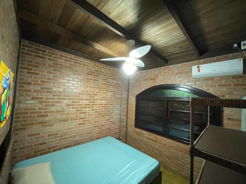 a room with a ceiling fan and a brick wall at Casa Vila Say 04 quartos ar e Piscina Aquecida in São Francisco do Sul