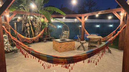 a hammock on a patio with a table and chairs at Casa Vila Say 04 quartos ar e Piscina Aquecida in São Francisco do Sul