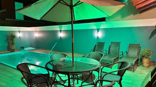 a table with chairs and an umbrella next to a pool at Casa Vila Say 04 quartos ar e Piscina Aquecida in São Francisco do Sul