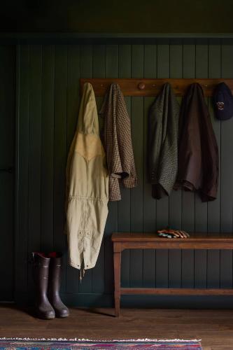 une étagère en bois avec des chapeaux et des bottes sur un mur dans l'établissement Maison de Reve avec Sauna en Pleine Foret, à Le Vaudoué