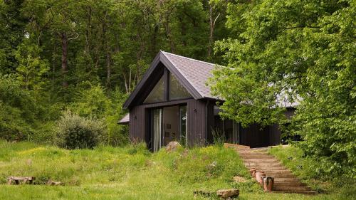 una capanna nera in mezzo a una foresta di Maison de Reve avec Sauna en Pleine Foret a Le Vaudoué