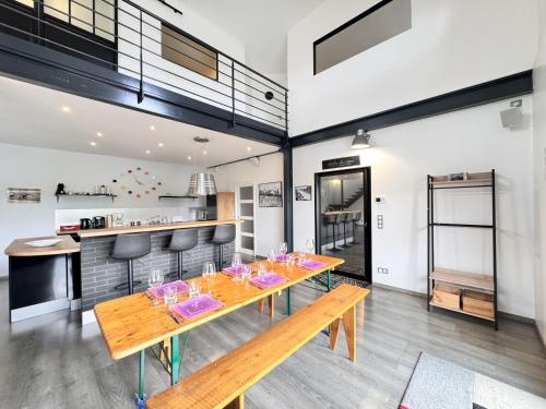 une salle à manger avec une table et des bancs en bois dans l'établissement Le Paddock - Video Projecteur - Jardin - 6 pers, au Mans