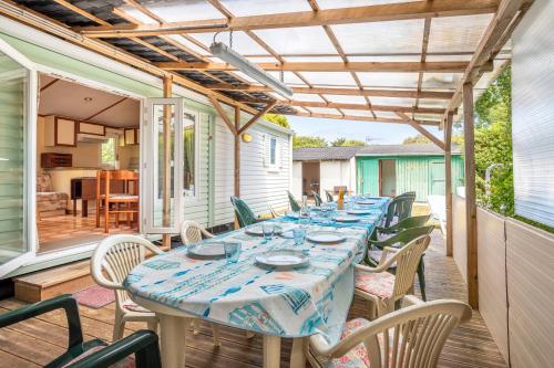 une terrasse avec une grande table et des chaises dans l'établissement Les Mimosas - Location Familiale, à La Brée-les-Bains