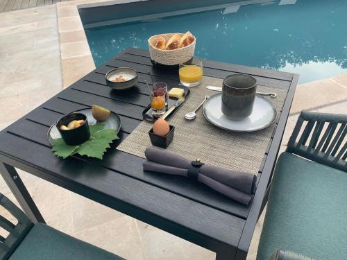 a table with food and drinks on it next to a pool at Le Clos 1855 in Saint-Laurent-des-Bâtons