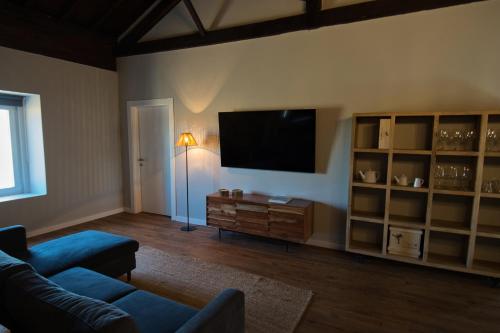 a living room with a tv and a blue couch at Sorraia Hotel Rural in Santa Justa