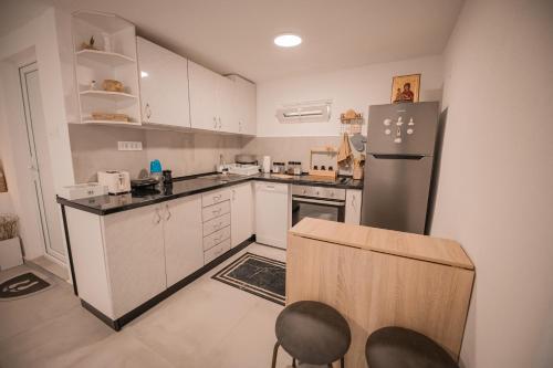a kitchen with white cabinets and a black refrigerator at Odisea House 2 in Ljubaništa