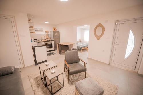 a living room with a couch and chairs and a kitchen at Odisea House 2 in Ljubaništa