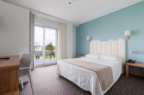 Un dormitorio con una cama y un escritorio y una ventana. en Hotel Azinheira by RIDAN Hotels, en Fátima