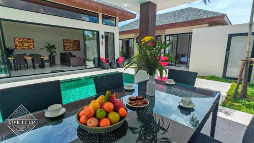 a table with a bowl of fruit on it in front of a house at Santi Tara Villas in Amphoe Koh Samui