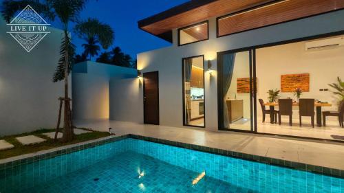 a villa with a swimming pool in front of a house at Santi Tara Villas in Amphoe Koh Samui