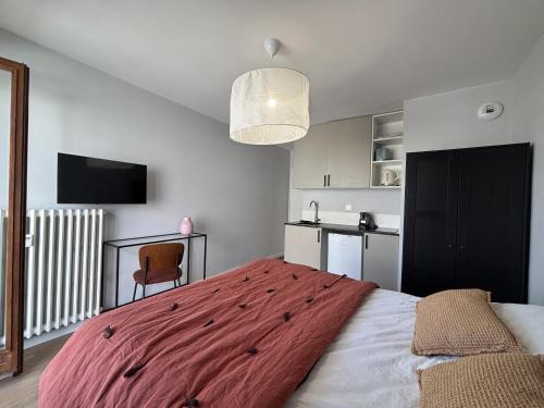 une chambre avec un grand lit avec une couverture rouge dans l'établissement M74 Marquer joli studio centre ville, à Annemasse