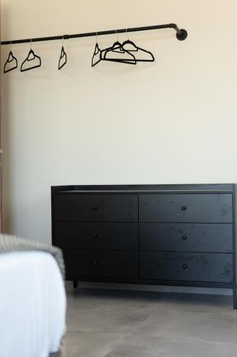a black dresser in a bedroom with a white wall at Eros sea view residences Mytilini in Agia Marina Lesvos