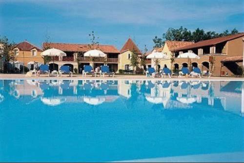 a large swimming pool with chairs and umbrellas at Lac Mondésir the little house and its Bastide in Monflanquin