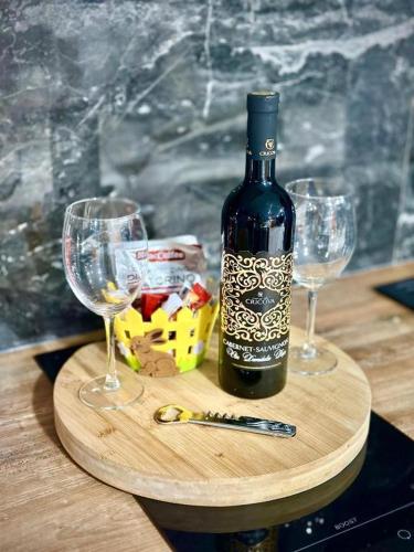 a bottle of wine and two glasses on a table at Vila Airport 24H in Chişinău