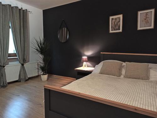 a bedroom with a bed and a black wall at Cztery Kąty w Rynku by LibertaRent in Wałbrzych