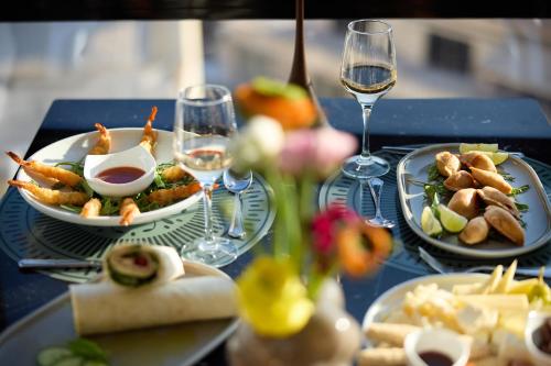 a table with two plates of food and glasses of wine at Astor Hotel Athens in Athens