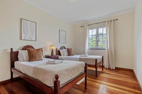 a bedroom with two beds and a window at Amendoeira Residence by Homie in Quinta do Almeida