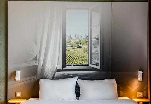 a bedroom with a window and a bed with white pillows at B&B HOTEL Bordeaux Est 3 étoiles in Tresses