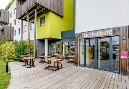 a group of tables and benches outside of a building at B&B HOTEL Bordeaux Est 3 étoiles in Tresses