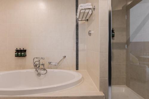 a bathroom with a white tub and a shower at voco Belfast by IHG in Belfast