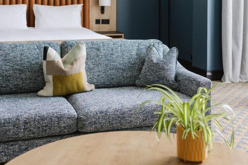 a blue couch with pillows in a room with a bed at voco Belfast by IHG in Belfast