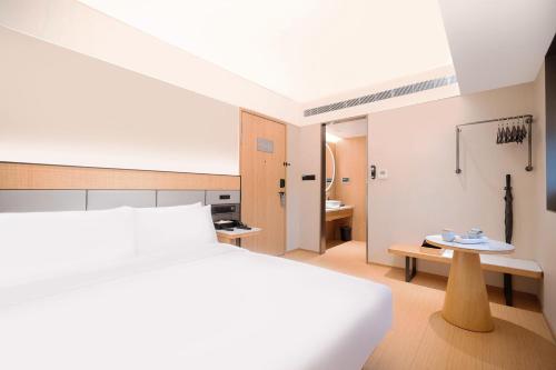 a bedroom with a white bed and a bathroom at Ji Hotel Orchard Singapore in Singapore