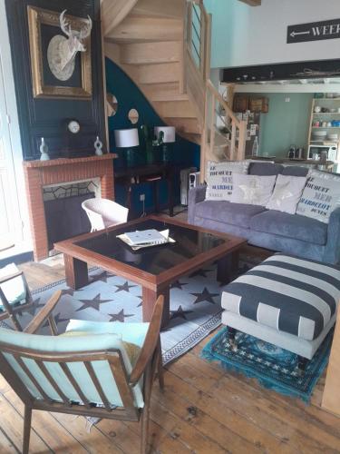 Una sala de estar con un sofá, una mesa y sillas. en La maison de la baie, wifi, terrasse, 200m du port, en Saint-Valery-sur-Somme