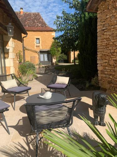 a patio with chairs and a table with a cat statue at Le Clos 1855 in Saint-Laurent-des-Bâtons