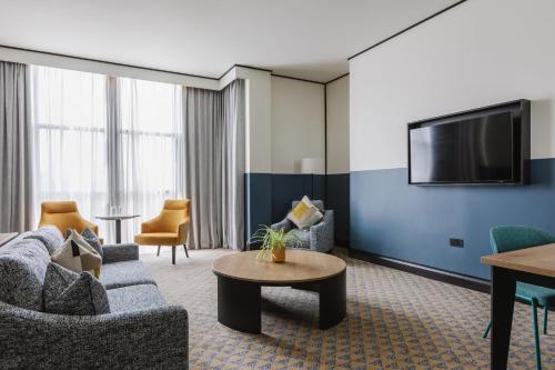 a living room with a couch and a tv at voco Belfast by IHG in Belfast