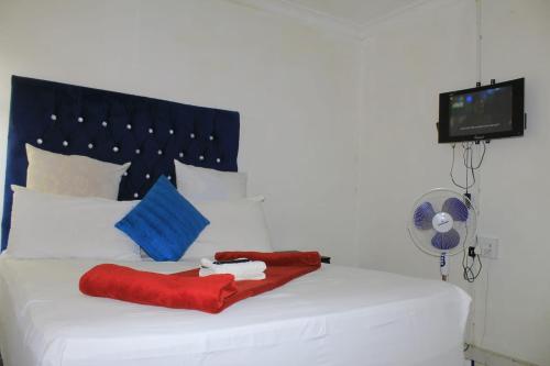 a white bed with red pillows and a fan at 26 Zea avenue Arcon Park Guest House in Vereeniging