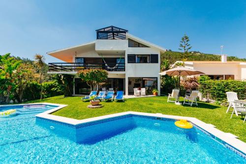 a villa with a swimming pool in front of a house at Panoramic Ocean View Villa & Pool in Sesimbra by Rent4Rest in Sesimbra