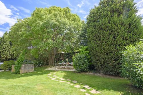 a garden with trees and a stone path at Mas du Micocoulier in Paradou