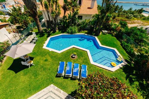 an overhead view of a swimming pool with chairs and an umbrella at Panoramic Ocean View Villa & Pool in Sesimbra by Rent4Rest in Sesimbra
