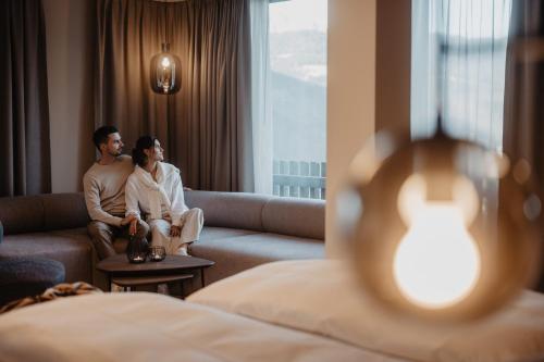 a man and woman sitting on a couch in a hotel room at Hotel Berghof - St Johann in Salzburg in Sankt Johann im Pongau