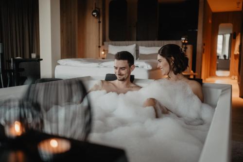 a man and a woman sitting in a bath tub filled with foam at Hotel Berghof - St Johann in Salzburg in Sankt Johann im Pongau