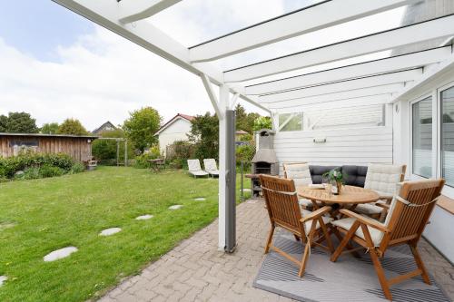 a patio with a table and chairs under a white pergola at Die Böttgerei Dünenkeiler in Dahme