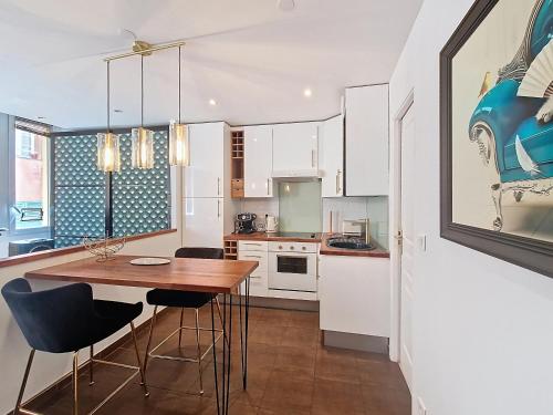 une cuisine avec des armoires blanches et une table et des chaises en bois dans l'établissement Nestor&Jeeves - REFLET DOR - Vieux Nice - Near beach, à Nice