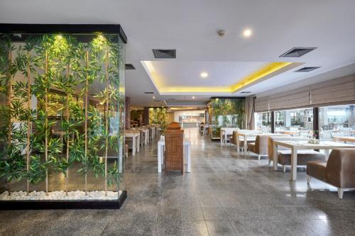 a restaurant with tables and chairs and a wall of plants at Asteria Family Resort Belek in Belek