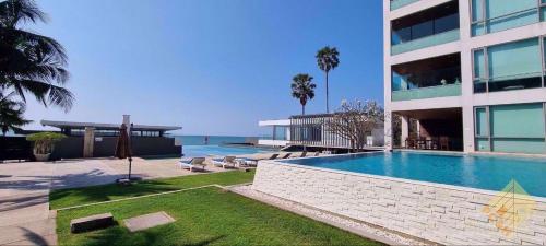a large building with a swimming pool next to the ocean at Beachfront Luxe with Pool Access and Terrace in Pattaya North
