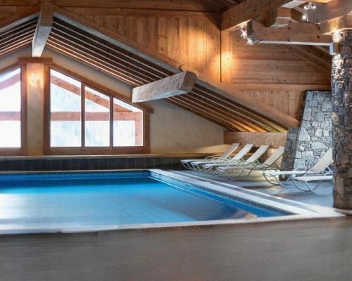 a swimming pool in a wooden house with chairs around it at L’Arolles Spa, Calme & Vue Montagne in Champagny-en-Vanoise